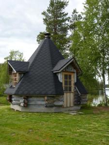 a small log cabin with a black roof at Karhujärven Kelopirtit in Karhujarvi