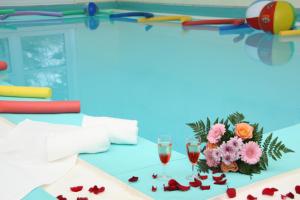 a table with two glasses of wine and flowers at Sporthotel Glück Auf Mönchenfrei in Brand-Erbisdorf