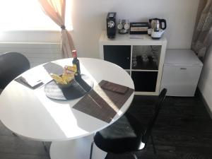 un tavolo bianco con una bottiglia di vino e una ciotola di banane di Chambre d'hôtes du Guéravet a Grolley