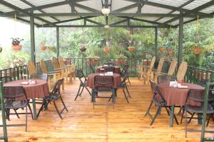 eine Terrasse mit Tischen und Stühlen auf einem Holzboden in der Unterkunft Alla Arriba in Las Cruces