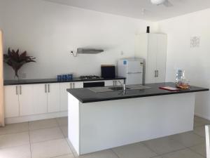 a kitchen with white cabinets and a black counter top at Ariki Dream Villa in Titikaweka