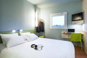 a bedroom with a white bed with a laptop and a desk at ibis budget Cabourg Dives sur Mer in Dives-sur-Mer