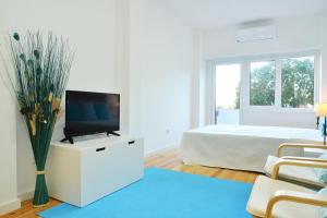 a white bedroom with a tv on a dresser and a bed at Real Home in Sacavém
