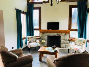 a living room with two chairs and a fireplace at Complejo Puelo Altos de Golondrinas in Golondrinas