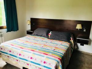 a bedroom with a large bed with a colorful comforter at Complejo Puelo Altos de Golondrinas in Golondrinas
