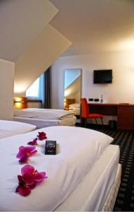 una camera d'albergo con tre letti e fiori sul letto di Ara Classic a Ingolstadt