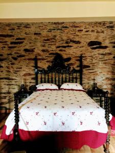 a bed in a room with a stone wall at Casa da Escola Antiga in Manteigas