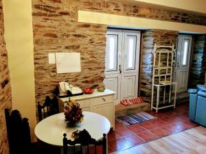 uma cozinha com uma mesa e uma parede de pedra em Casa da Escola Antiga em Manteigas