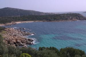 vista su una spiaggia con rocce e acqua blu di VIlla Ulivi a Chia