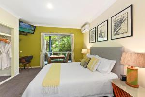 1 dormitorio con 1 cama blanca grande y paredes verdes en Azura Beach House B&B en Port Macquarie