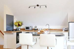 una cocina con electrodomésticos blancos y taburetes blancos en Dove Lodge, en Painswick