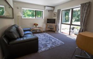 a living room with a leather couch and a television at Bellbird Guest Accommodation in Akaroa