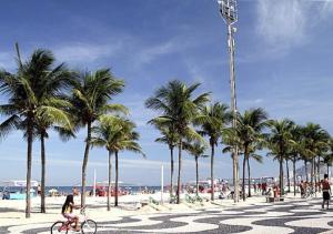 una mujer montando una bicicleta en una playa con palmeras en Copacabana Vista Cristo Redentor, en Río de Janeiro