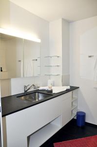 a white bathroom with a sink and a mirror at La Perla A1 in Scuol
