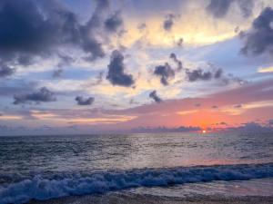 een zonsondergang op het strand met de oceaan bij At Home Khaolak in Khao Lak