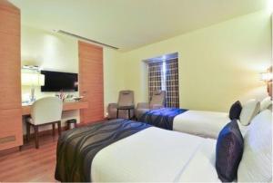 a hotel room with two beds and a desk at Middleton Inn in Kolkata