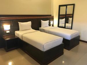two beds in a hotel room with a mirror at Room Place in Chumphon