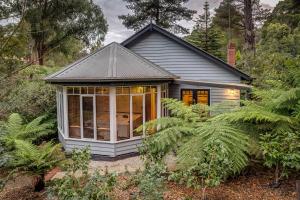 a small house in the middle of a garden at Fern Falls Cottages - Garden Cottage in Mount Dandenong