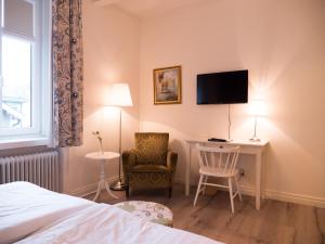 a hotel room with a bed and a desk and a tv at Hotel Åberg Centralhotellet in Tranås