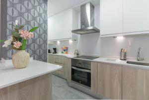 a kitchen with white cabinets and a vase of flowers on a counter at Plaza España & Gran Via 2BD 1BTH in Madrid