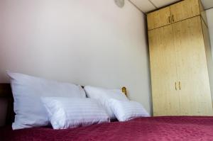 a bed with white pillows and a wooden cabinet at Pensiunea Georgibel in Deva