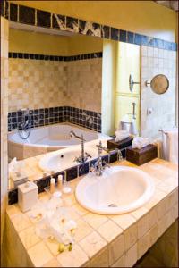 a bathroom with a tub and a sink and a mirror at Auberge A La Bonne Idée in Saint-Jean-aux-Bois