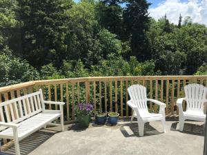Dos sillas blancas sentadas en un patio con plantas en Sycamore Villa, 2 bedroom apartment en Dunedin