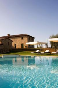 a large swimming pool with two benches and a building at Villa il Castagno Wine & Resort in Siena