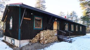 a black house with a pile of logs in front of it at Stena Cabins & Apartments in Äkäslompolo