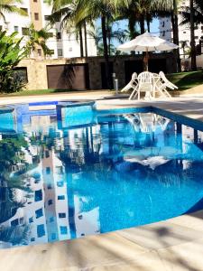 uma piscina com água azul e um guarda-sol em Riviera de São Lourenço em Bertioga