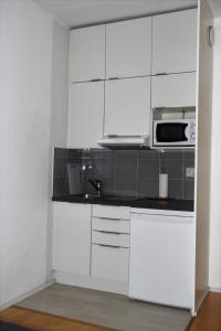 a kitchen with white cabinets and a microwave at Studio in Helsinki city center in Helsinki