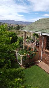 a brick house with a fence with flowers on it at Clarens Cottages in Clarens