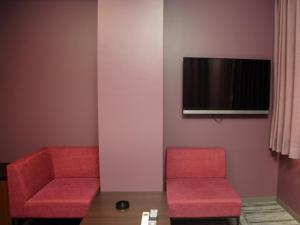 two red chairs and a table in a room at Hotel Neo World in Osaka