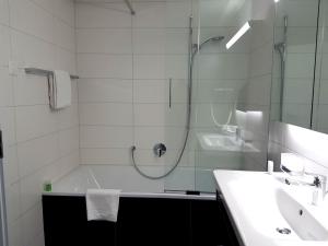 a bathroom with a shower and a tub and a sink at Apartment Silberdistel - GriwaRent AG in Interlaken