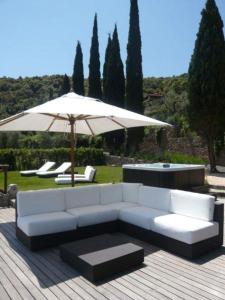 - un canapé blanc et un parasol sur la terrasse dans l'établissement Villaflair - Design Villa Porto Ercole, à Monte Argentario