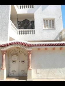 Edificio blanco con puerta y balcón en Nice Holiday Apartment Hammam Sousse, en Hammam Sousse