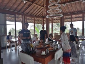 un grupo de personas sentadas alrededor de una mesa en un restaurante en Melanting Cottages, en Munduk