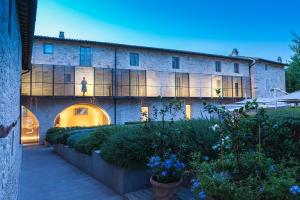 a large stone building with a woman standing on the balcony at Nun Assisi Relais & Spa Museum in Assisi