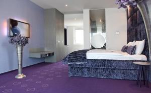 a hotel room with a bed and a vase of flowers at G Design Hotel in Ljubljana
