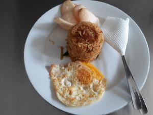 a white plate with breakfast food on a table at Melanting Cottages in Munduk