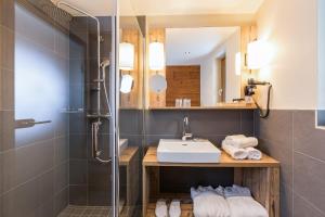 La salle de bains est pourvue d'un lavabo et d'une douche. dans l'établissement Alpenhotel Tirolerhof, à Fulpmes