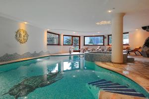 una grande piscina in una casa con sedie di Hotel Touring a Madonna di Campiglio