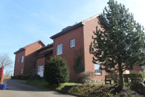 a red brick building with a tree in front of it at Küstenzauber in Schönhagen