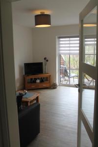 a living room with a couch and a television and a table at Küstenzauber in Schönhagen