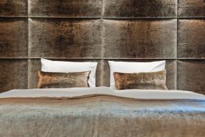 a bed with four pillows in front of a wall at G Design Hotel in Ljubljana
