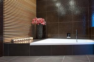 a bathroom with a bath tub with a vase of flowers at G Design Hotel in Ljubljana
