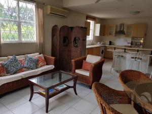 a living room with a couch and chairs and a table at 3 Springcourt Apartment in Bridgetown