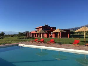 een zwembad met stoelen en een huis op de achtergrond bij Finca Albarossa in Fuerte Quemado