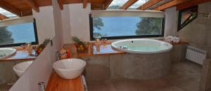 a bathroom with a tub and two sinks and a large window at Amarras in Villa Pehuenia