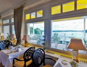 ein Esszimmer mit Tischen und Stühlen und einem großen Fenster in der Unterkunft Vitalia Seehotel in Bad Segeberg